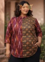 Woman wearing Boriby plus size shirt with maroon ikat and earthy geometric patterns, mandarin collar, button‑down front, outdoor background.