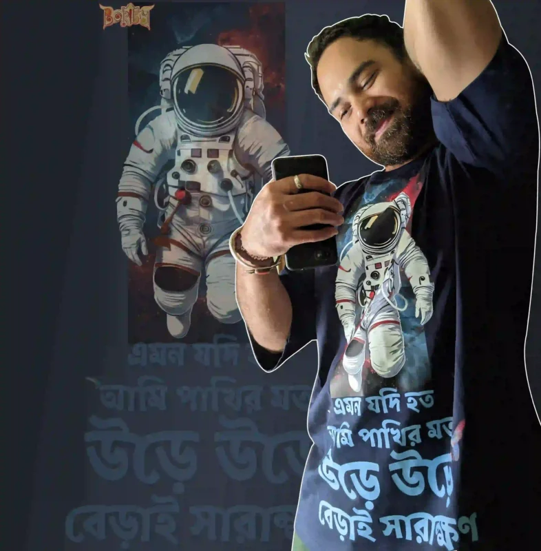 Person wearing Boriby oversized cotton T‑shirt with astronaut space graphic and Bengali typography, selfie with matching background design