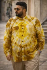 Plus size man standing outdoors in Boriby yellow and brown tie dye Bhagalpuri silk shirt with chest pockets, paired with beige pants and sunglasses