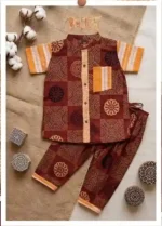 Flat lay of children’s cotton shirt and pants in Ajrakh patchwork print with orange striped pocket and cuffs, artisanal background.