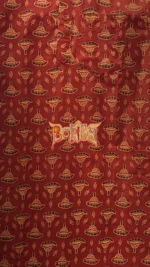 Close‑up of red Ajrakh cotton kurta fabric with yellow and black motifs and Dorby branding