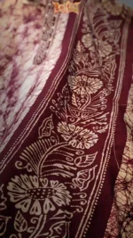 Close‑up of maroon batik cotton fabric with cream floral motifs
