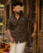 Man wearing Ajrakh printed half shirt with white dhoti in festive temple background