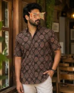 Man in Ajrakh printed half shirt with light pants in rustic indoor setting
