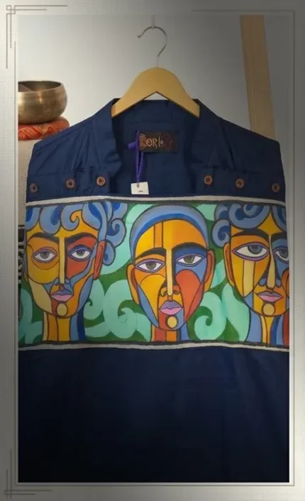 Dark blue Boriby kurta with hand‑painted abstract faces and colorful geometric motifs displayed on hanger